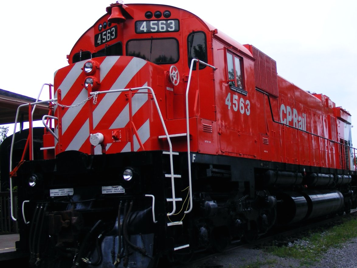 a red train stopped on the tracks next to a station