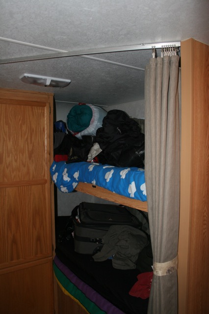 there is a bunk bed with clothing on top