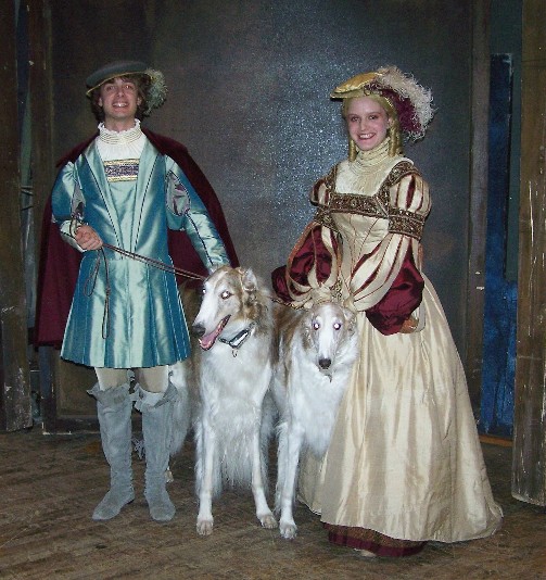 two young people in period outfits posing with dogs