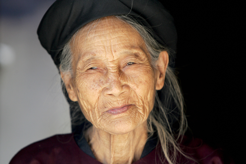 an old woman wearing a hat is looking at the camera