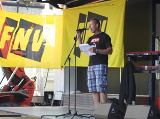 a man talking into a microphone with a yellow banner in the background