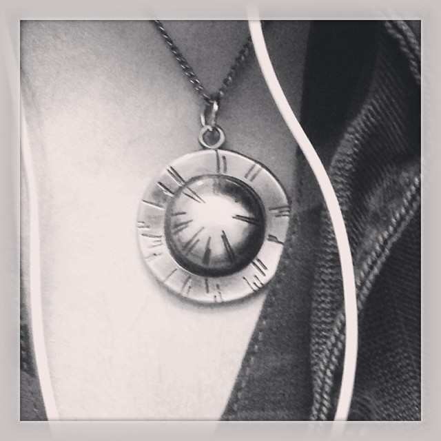 a necklace with a clock in the middle on it