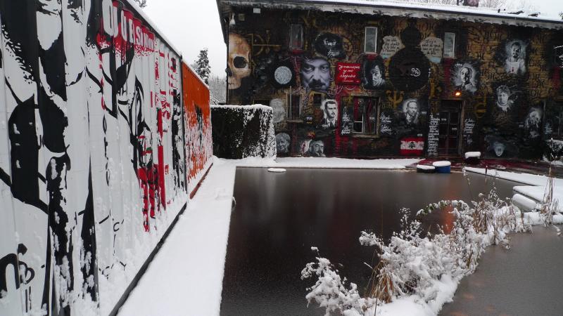 an industrial building covered in graffiti with a large building next to it