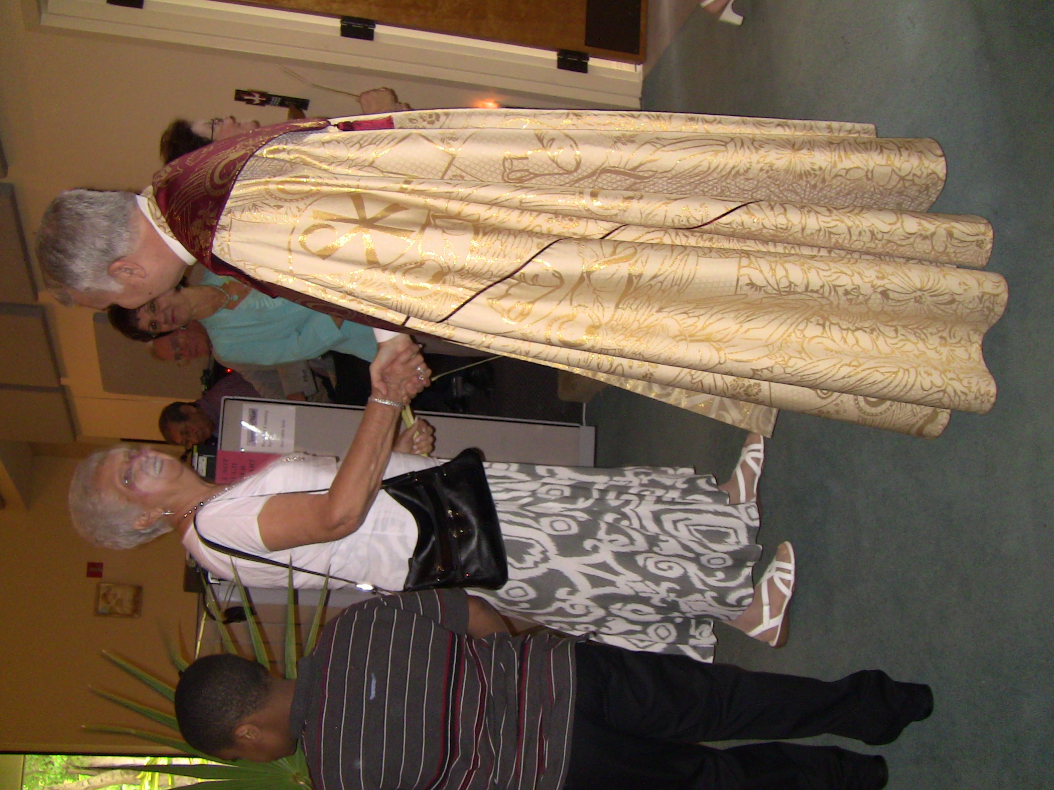 two women shaking hands in a room full of people