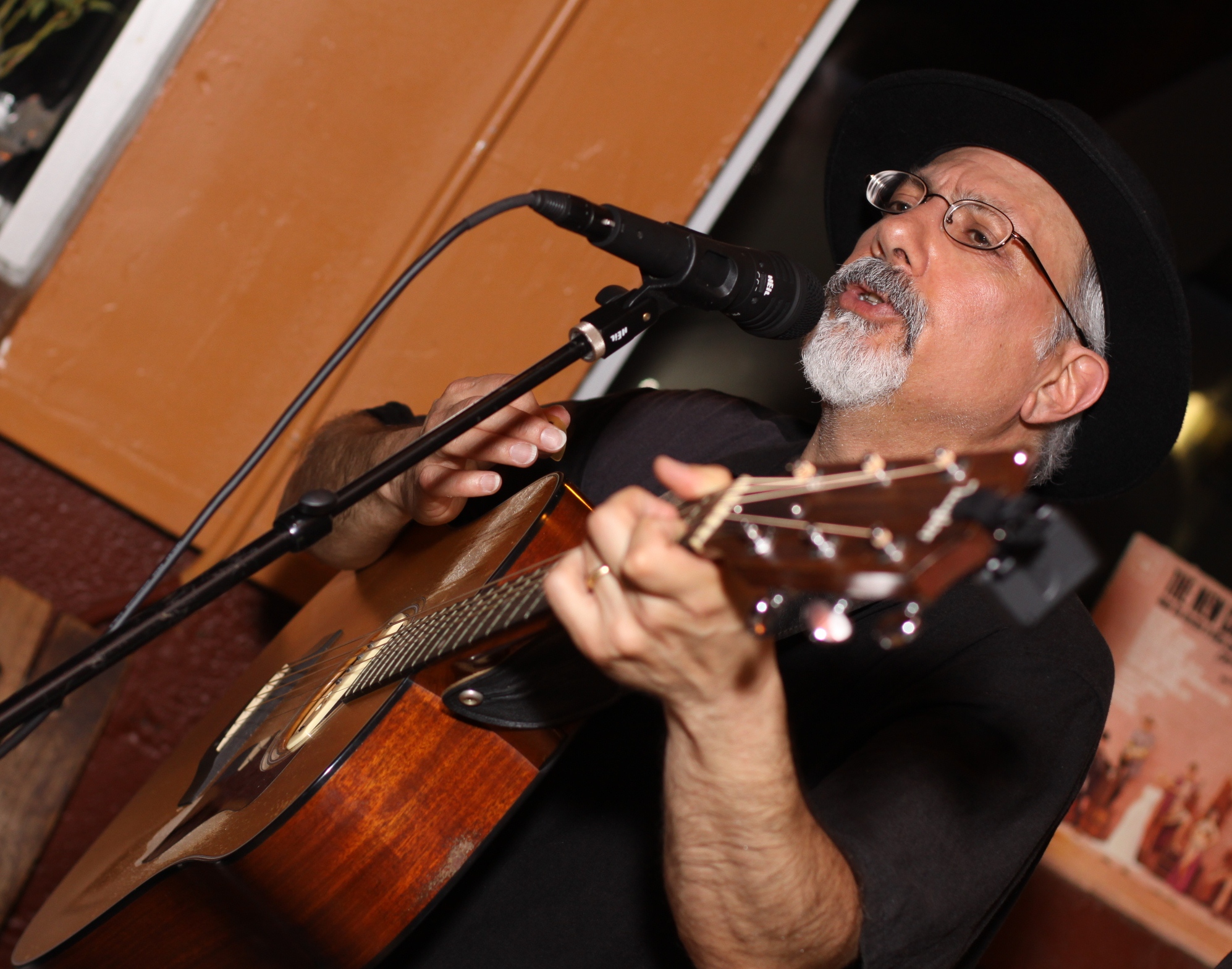 an older man playing the guitar while singing into a microphone