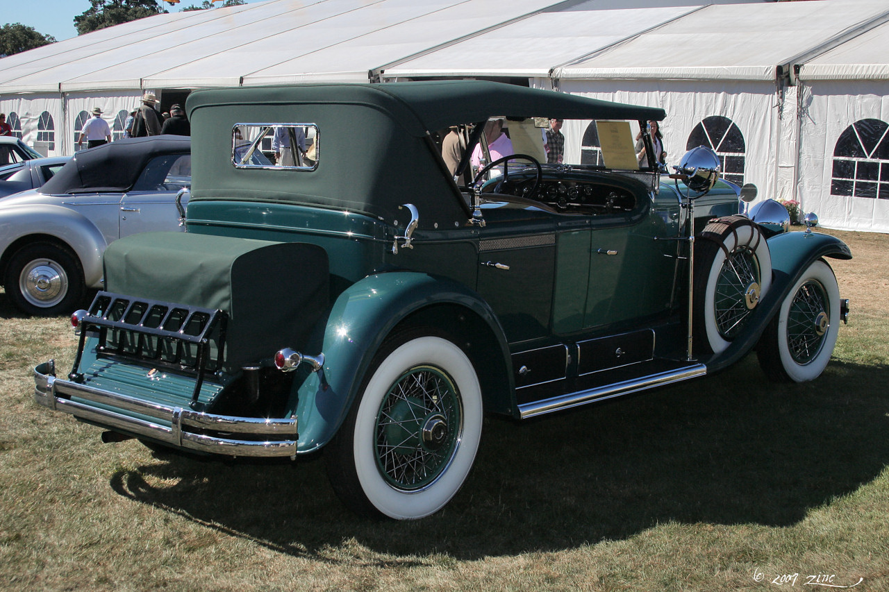 a vintage green car at a car show with a man in the cab