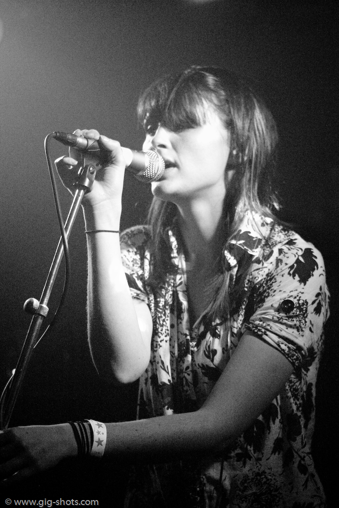 a female singer singing into a microphone with a white spotlight in the background