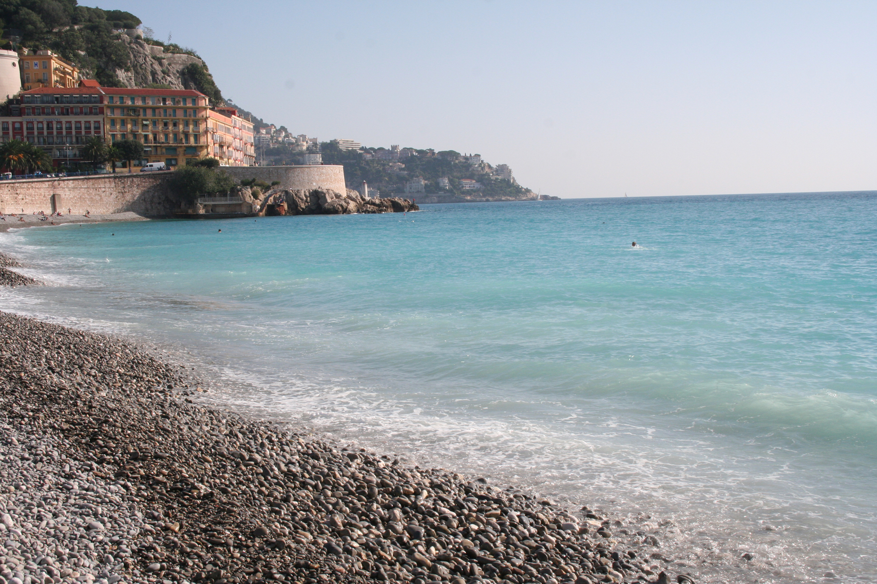 the waves hit the beach with the cliffs to the left