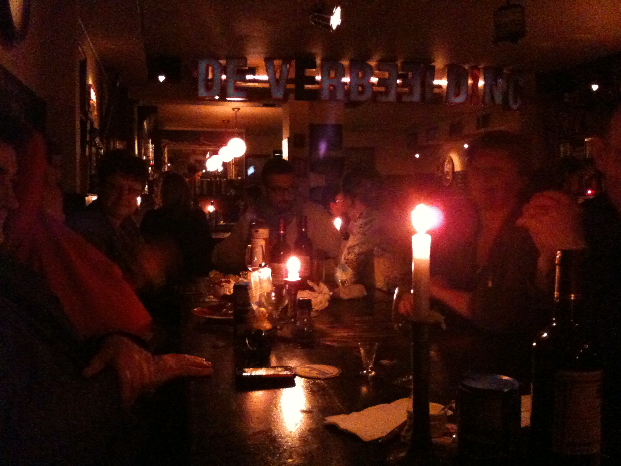 people sitting around a dark dinner table in a restaurant with lit candles