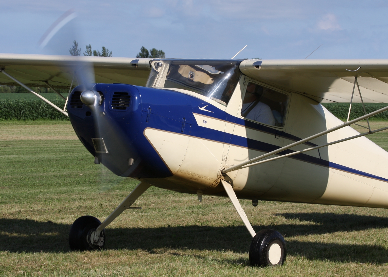 a small, propeller plane on a field with grass