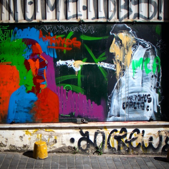 a large graffiti covered wall with people in colorful clothing