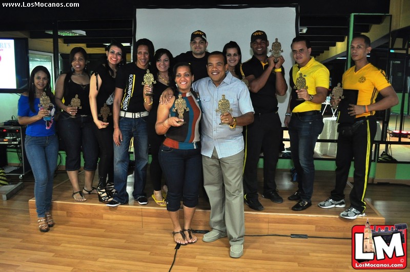 a man holding a trophy stands in front of a group of people