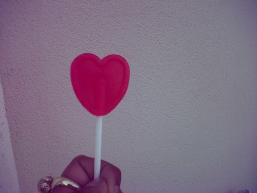 someone holding a candy heart stick in their hand