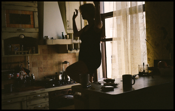 a woman standing in front of a window with a coffee cup