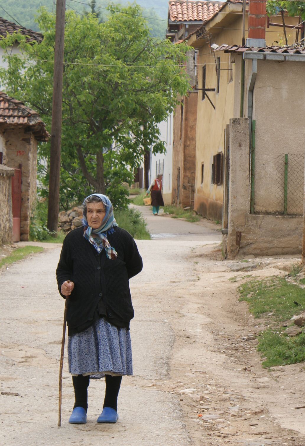a woman walking down a street in front of buildings