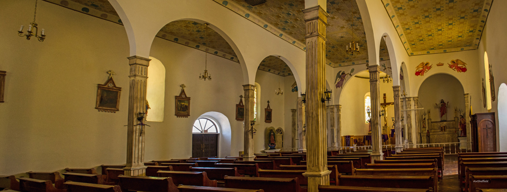 rows of pews inside of a building with arched windows