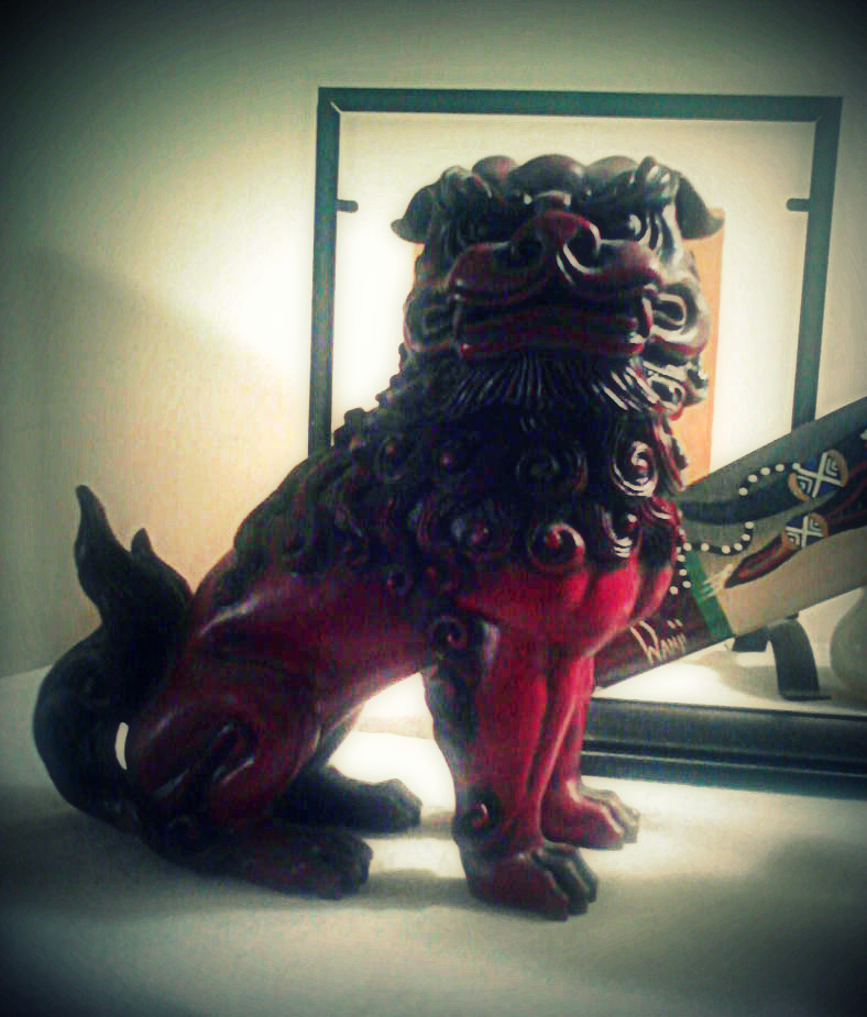 a red sculpture with a lion on it next to a mirror