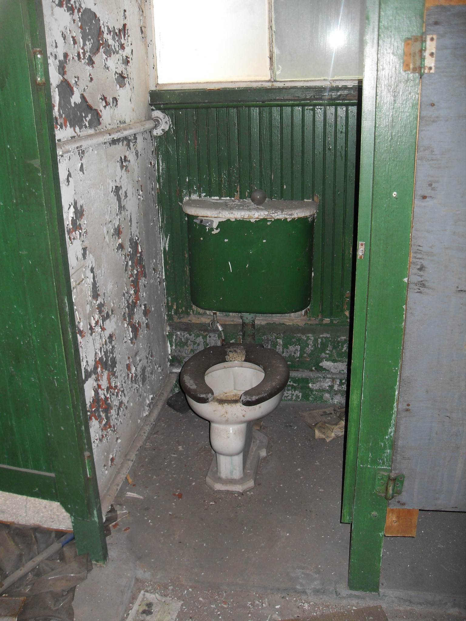 a nasty green bathroom has broken doors