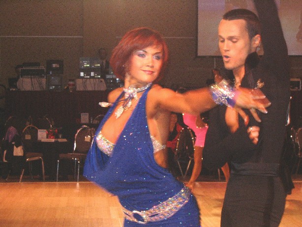a couple performing an salsa dance in a darkened ballroom