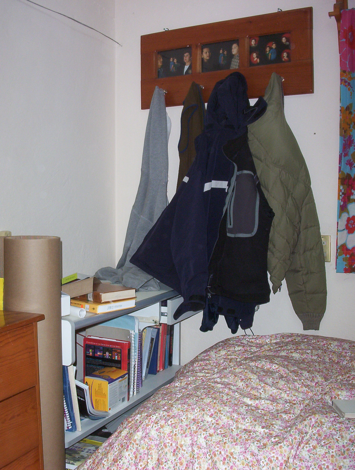 a room with a bed, bookcase, and coat rack