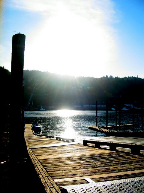 the sun shining down on a dock and the water