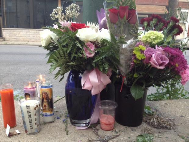 flowers, candles, and pictures sitting on the sidewalk