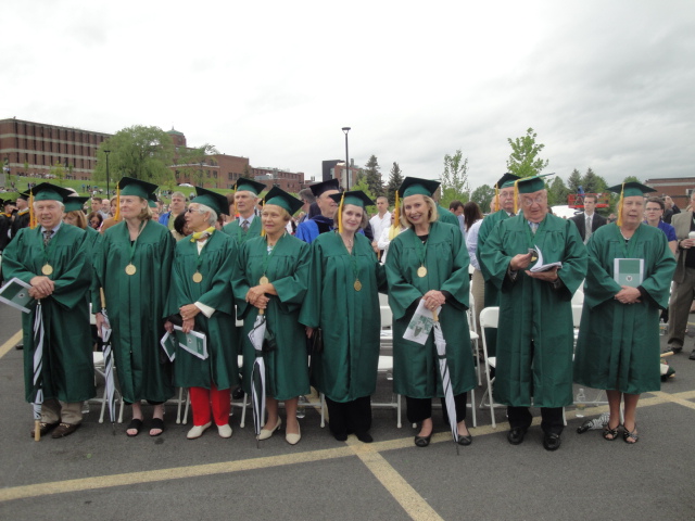 people standing and sitting in graduation regalia