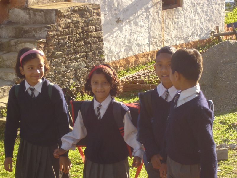 four children standing outside in uniforms and hats