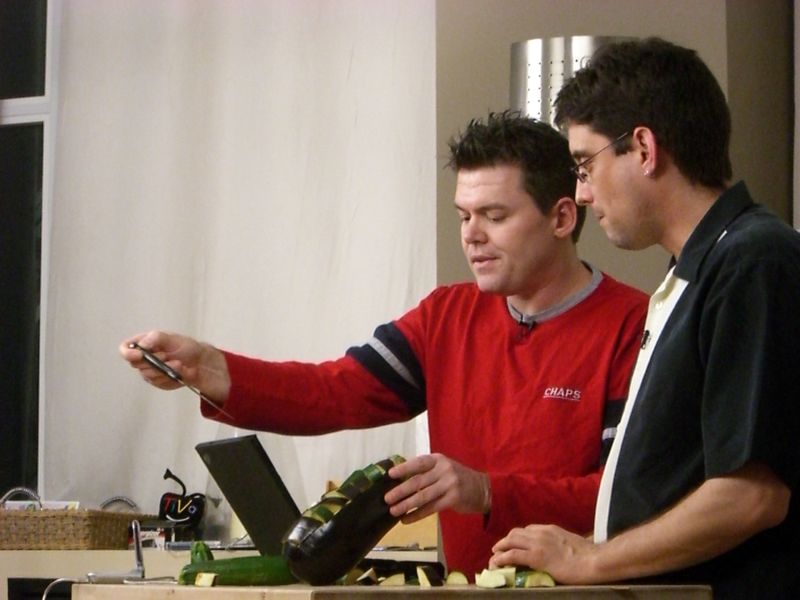 two men looking at a bottle of wine while standing up