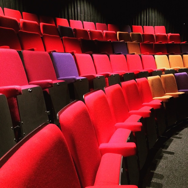 rows of empty red and yellow seats in an auditorium