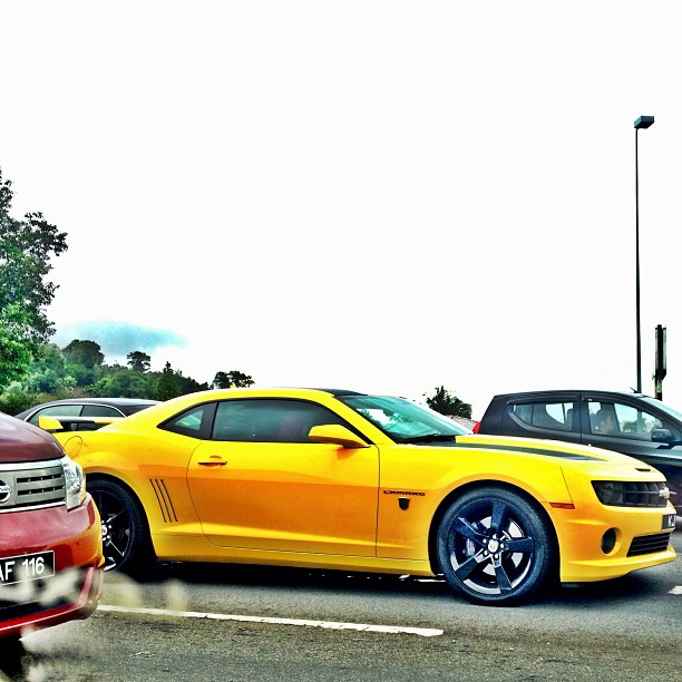 a yellow camaro sits parked in the parking lot