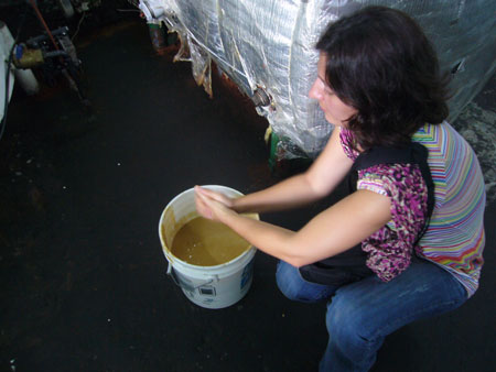 a woman is stirring a tub of brown liquid