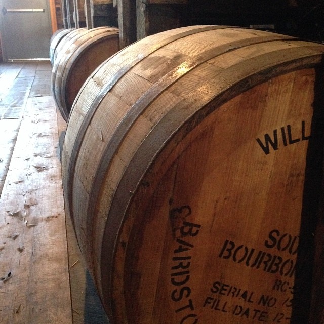 several wine barrels are lined up and one barrel is empty
