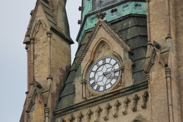 the view from below of a church spire with a large clock