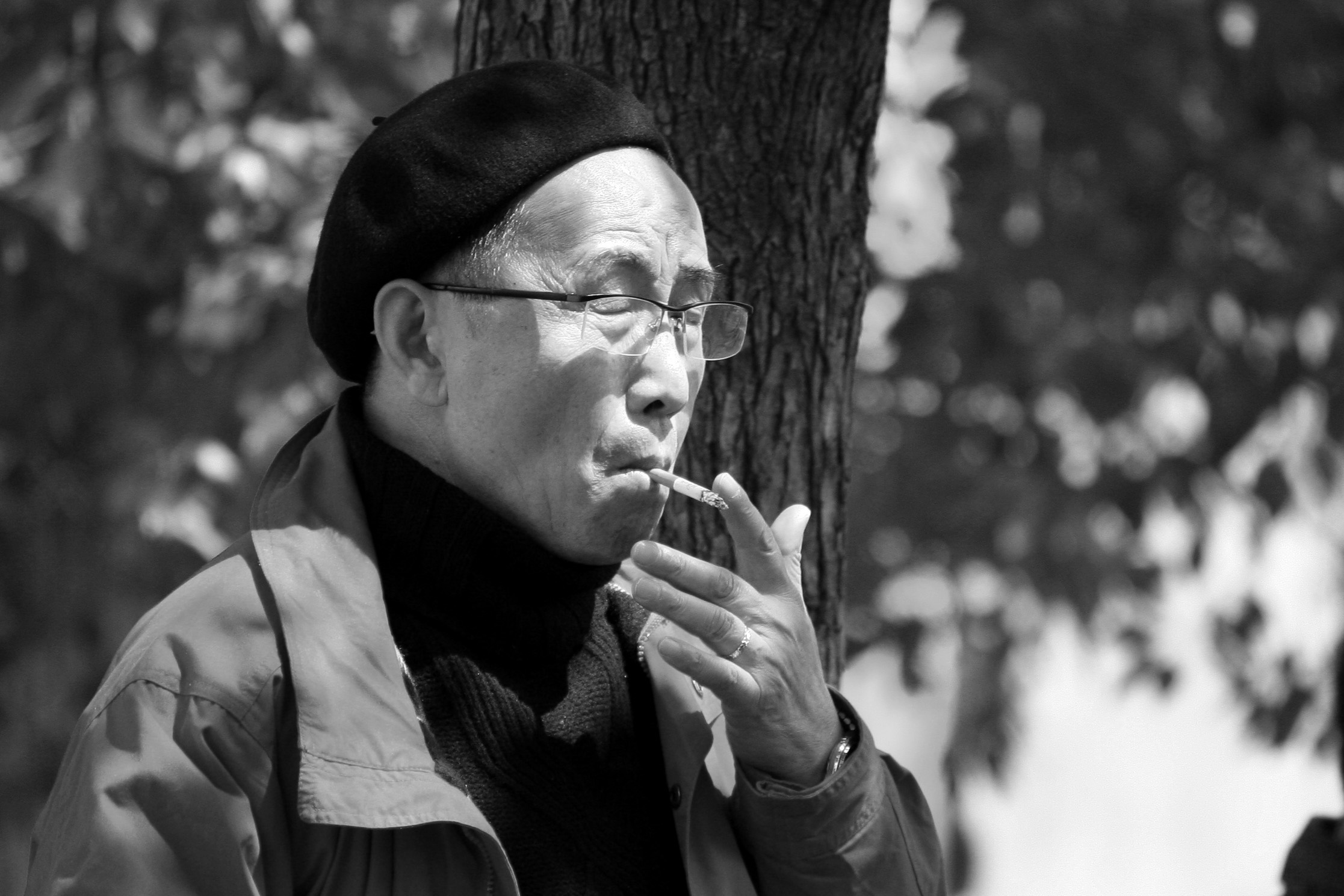 a man is holding a cigarette near a tree