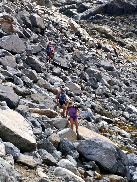 two people hike up a rocky trail with large boulders