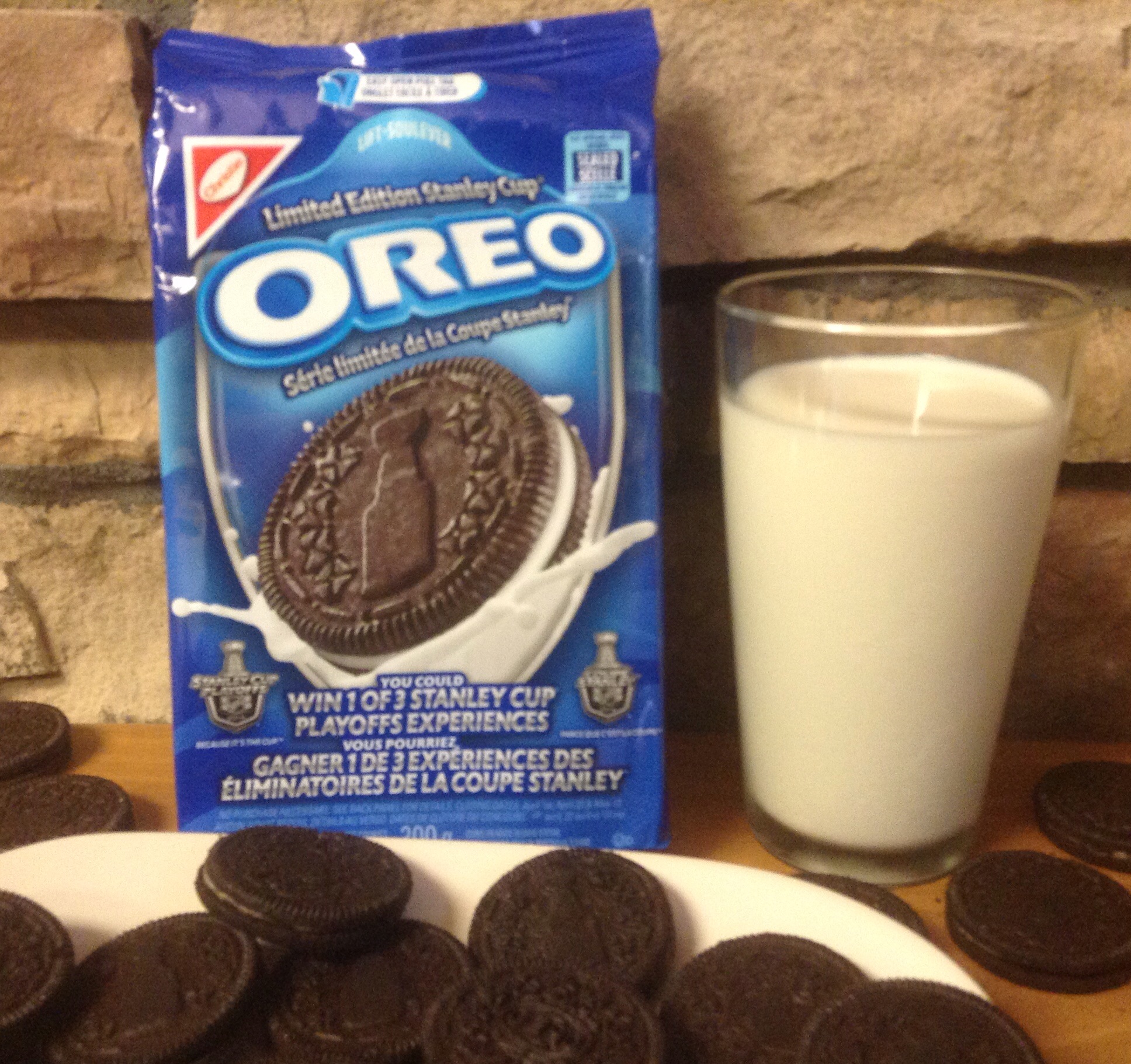 chocolate oreo cookies next to milk in front of a glass of milk