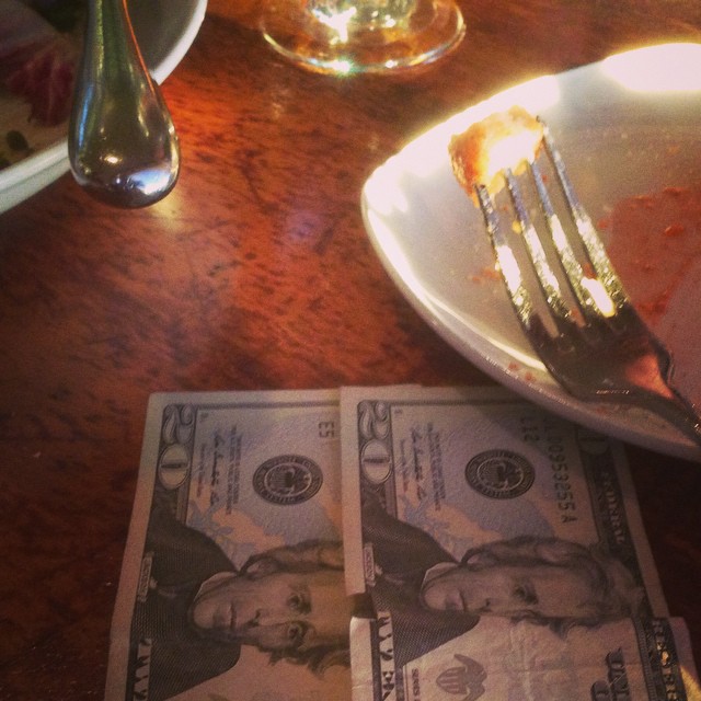 a plate of half - eaten pizza next to money
