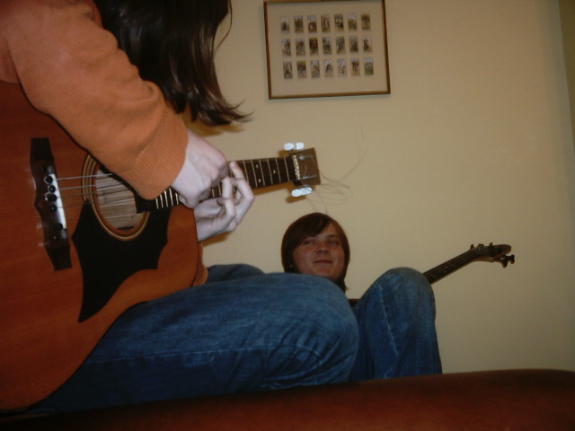 a person holding an acoustic guitar in front of another person