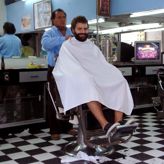 a barber cuts the hair of a young man