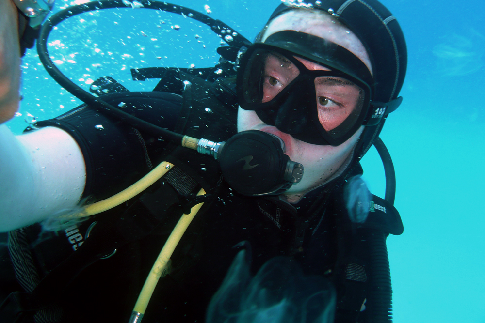a scuba with a scuba helmet on holding onto the side of his mask