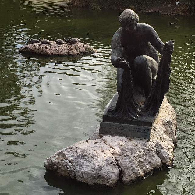 there is a statue on the rocks near the water