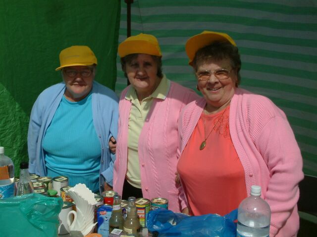 three ladies are standing at a table covered with condiments