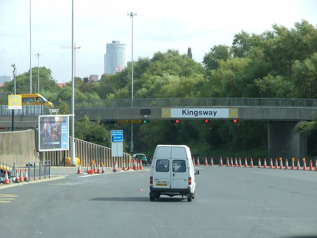 a van on the road with traffic cones on both sides