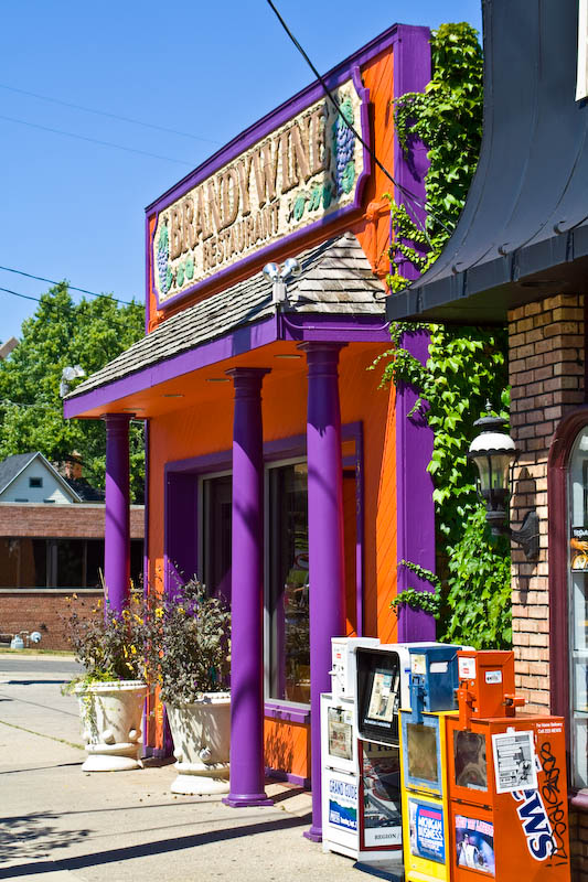 a purple and orange storefront is on the corner of a street