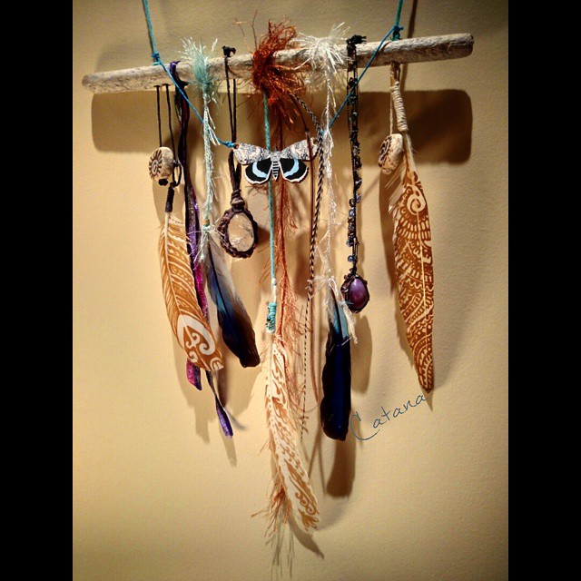several feathery items hang on a wood beam with sunglasses