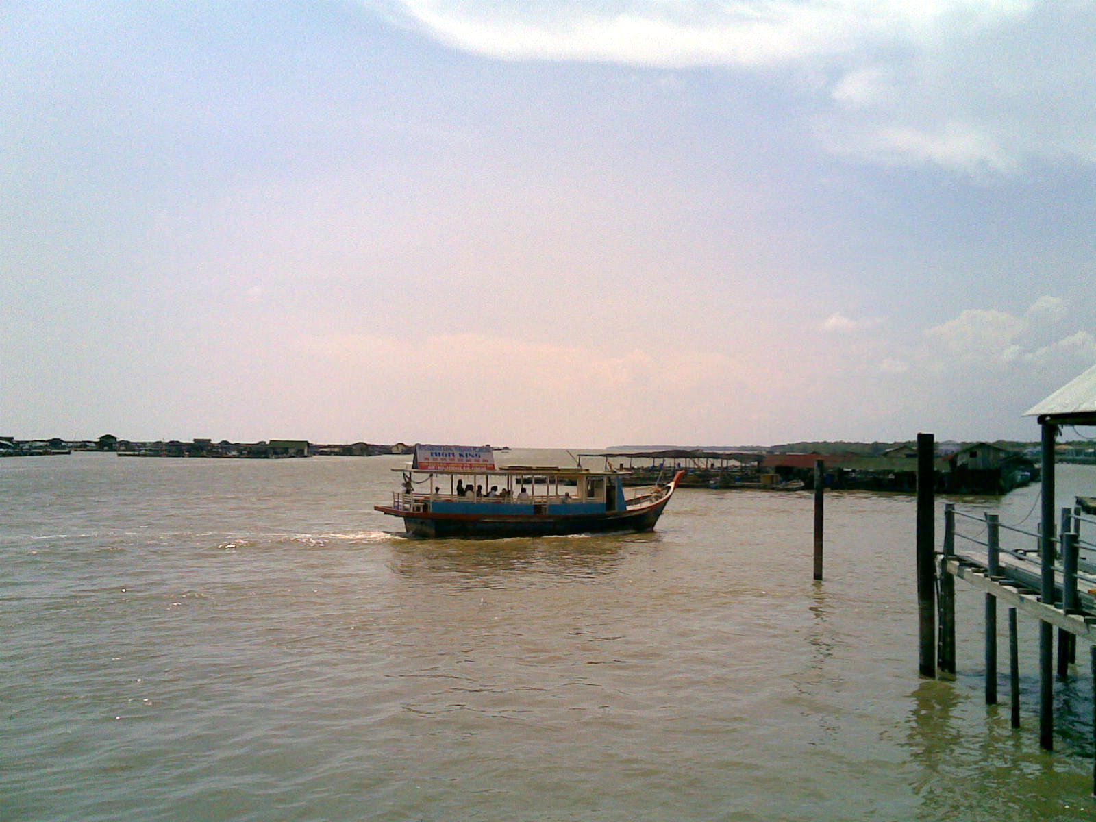 boat on river with bridge in distance and cloudy sky