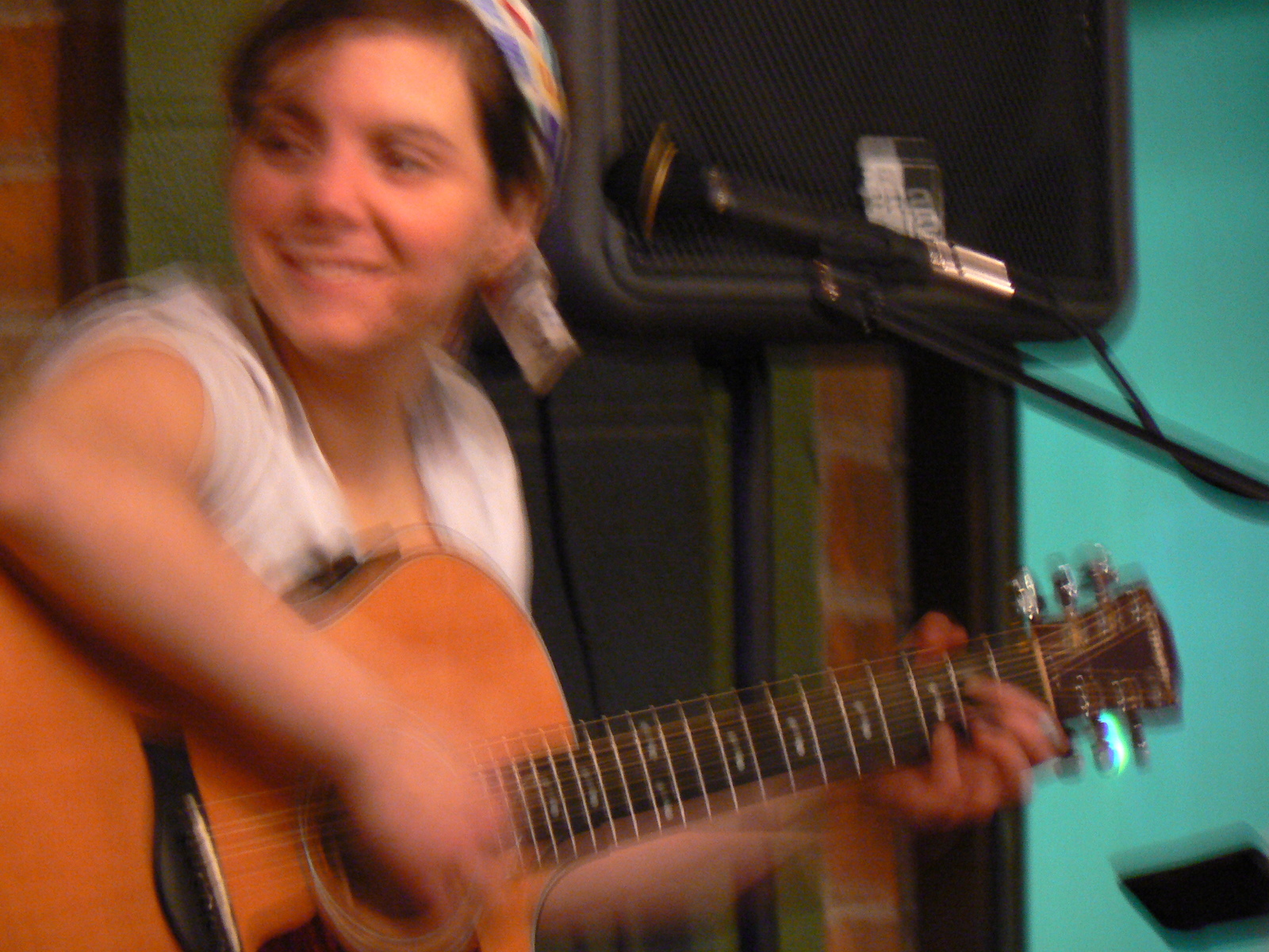 a man playing an acoustic guitar near a mic and a blue wall