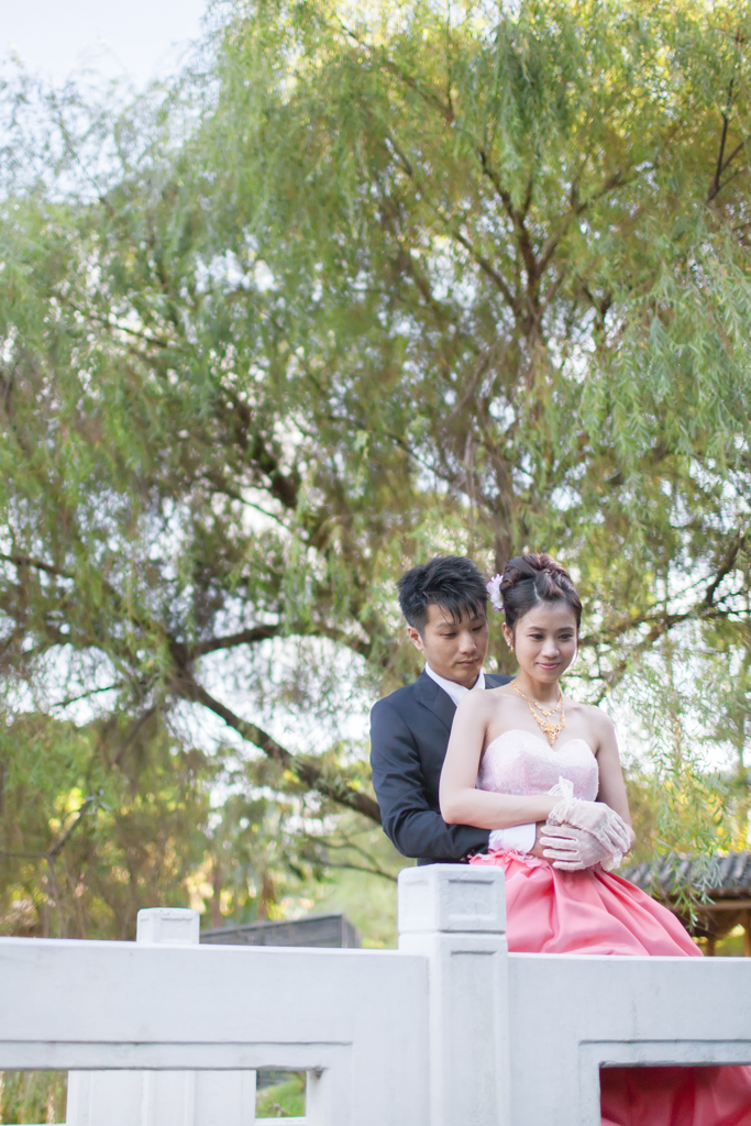 couple posing together on white bridge near trees