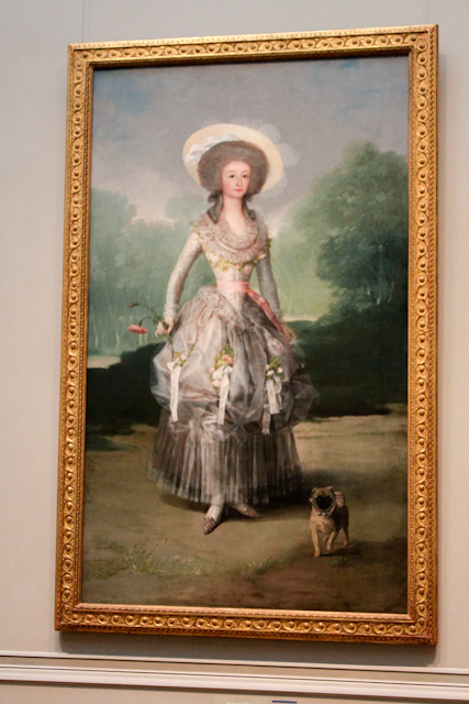 a lady with hat and dress painting hangs on a wall
